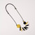 Necklace with round coin-shaped yellow and black beads with multiple oblong beads of black, yellow and white in between strung on black laying flat