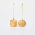 Pair of earrings consisting of 2 coin-shaped pale wood disks suspended from thin gold-toned elongated hoops