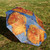 Van Gogh sunflower umbrella shown open and resting on the grass