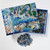 Top view of the puzzle box opened slightly to reveal the pieces inside, with a small pile of pieces below the puzzle.