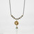 Close-up shot of a pendant necklace with a pearl and turquoise bird's nest design.