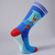 Philadelphia's Champion Socks are shown on a sock form in side and back view. The champion  boxer stands on a plinth,  with the museum's facade in the background. The socks are primarily blue and red, with stripes at the top and red toes and heels.