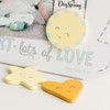 Three fun-shaped wood composite magnets are included, allowing for the display of precious baby photos. The frame stands on a folded metal easel, making it easy to place on a shelf or table. This decorative piece combines warmth and faith, making it a perfect addition to a nursery or as a thoughtful gift for new parents.