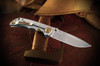 Function Meets Heritage – Strength in Every Detail
The lock side of the Marching Spartans Folder reflects Spartan practicality and resilience. Built from durable 6AL4V titanium and fitted with a robust frame lock, this side is all about performance. Bronze-anodized hardware—including the pivot, backspacer, and clip—adds refined contrast while tying the design back to the ancient bronze armor of the Spartans. Clean, functional, and fortified with the same no-nonsense reliability that defined a warrior’s gear, the lock side balances the symbolic detail of the presentation side with pure utility. Strong, secure, and battle-ready—just as a Spartan would demand.