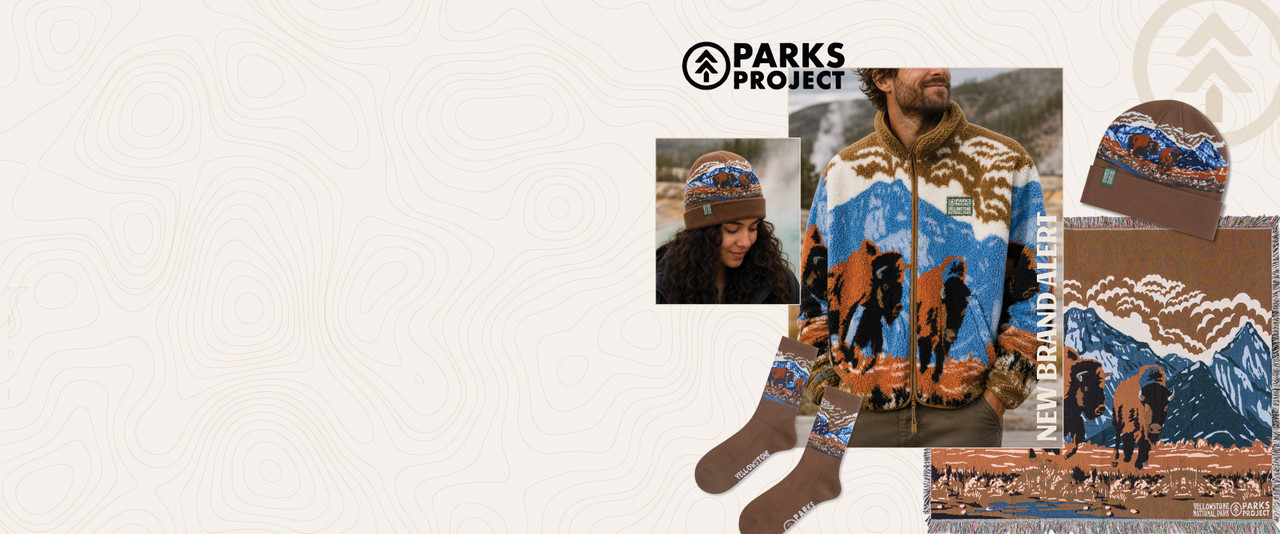 woman in beanie and man in fleece jacket surrounded by socks and a throw blanket all with a Yellowstone buffalo inspired design by Parks Project