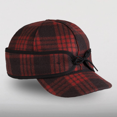 A 45 degree angle view of The Millie Kromer Cap: a wool, six-panel winter cap with a pulldown earband that ties in front, and a brim.