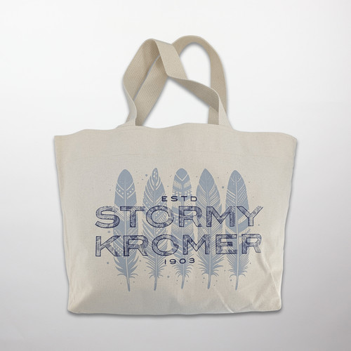 A natural colored tote bag printed with feathers and Stormy Kromer.