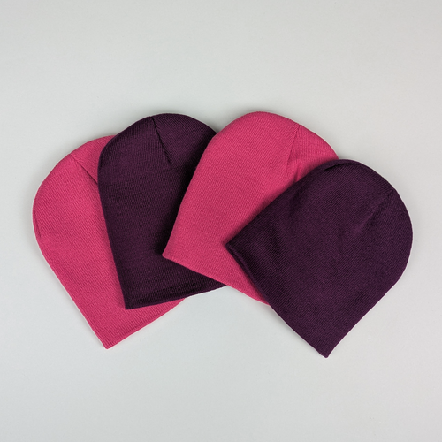Nine possible colors of acrylic knit beanies fanned out on a white background.