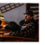 Man sitting on a wood chair with a black lab dog next to him.
