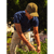 Man tending a garden, wearing a blue tshirt and an olive green waxed baseball hat.