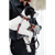 Man holding a black and white puppy wearing a red/black collar and leash.