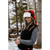 Photo of woman in her 20s with long hair standing in a snowy forest, laughing, wearing a black Stomy Kromer vest and a red/black plaid Stormy Kromer Aviator Hat.