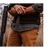 Man wearing a cap and wool vest over gray shirt holding an open shotgun on a bird hunt.