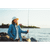 Lady wearing a blue shirt and white sweater holding a fishing pole at the shore wearing a natural colored Breakwater bucket hat.