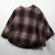Ladies poncho in tan, red, and black plaid.