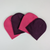 Nine possible colors of acrylic knit beanies fanned out on a white background.