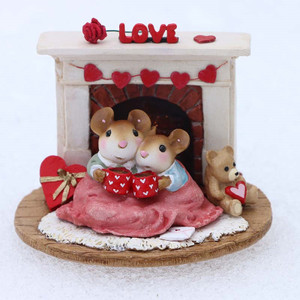 A Wee Forest Folk miniature Valentine's Day figurine of two tiny mice cuddled together in front of a fireplace decorated with hearts.