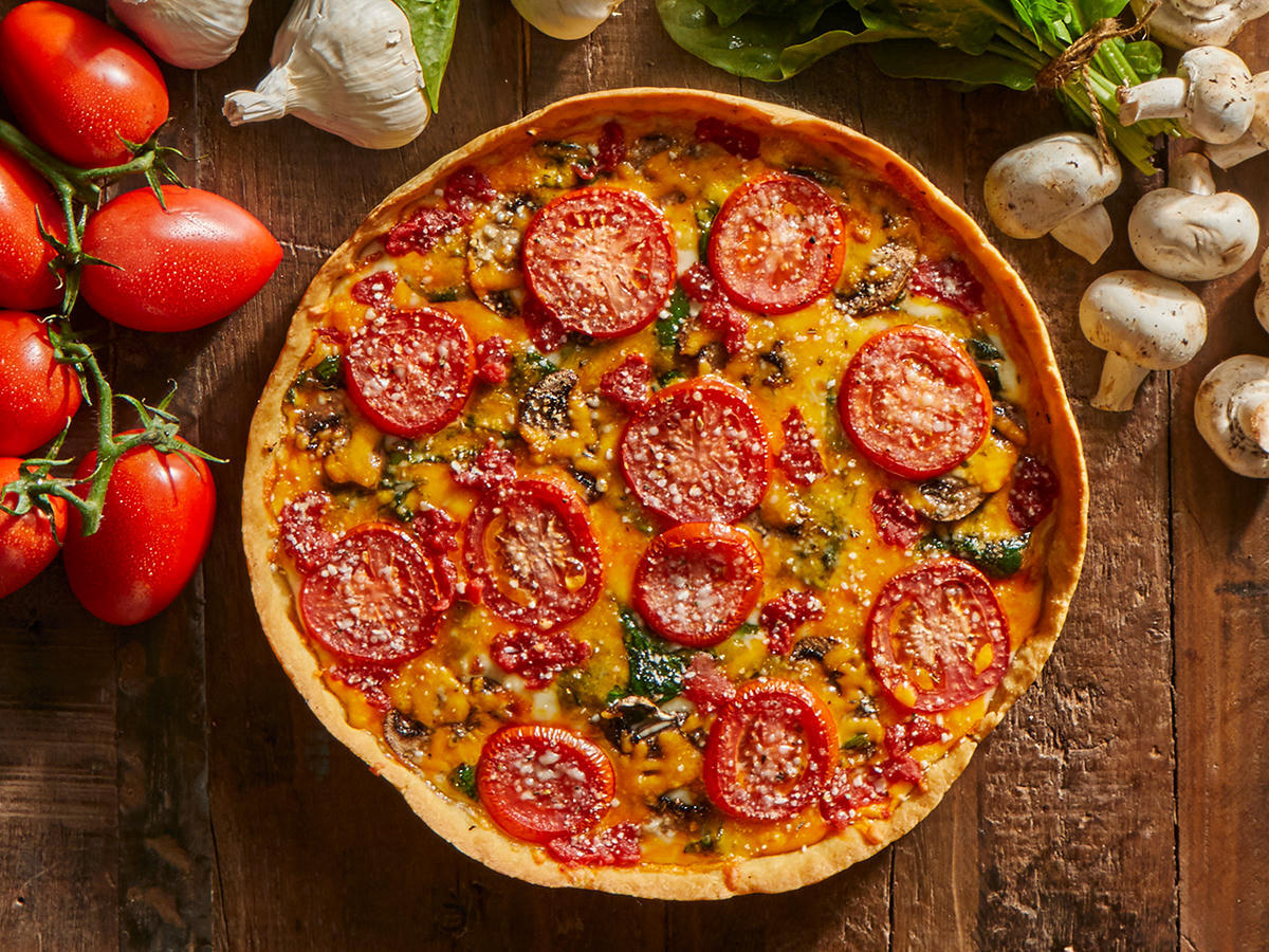 Lou Pizza with Tomatoes, Mushrooms, Spinach, and Cheddar, surrounded by fresh ingredients.
