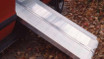 Folding aluminum curb ramp positioned at the back of a vehicle