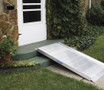 Portable aluminum curb ramp positioned against a front door, facilitating access for mobility devices