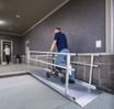 Man using a portable aluminum ramp to assist a wheelchair