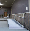 Portable aluminum curb ramp with handrails providing accessibility to a building entrance