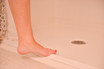 Foot stepping onto a shower stall threshold