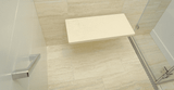 Curbless shower with a beige shower bench and linear drain