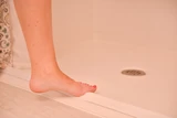 Foot stepping onto a shower stall threshold