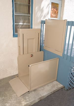 Bruno Vertical Platform Lift installed outdoors, with a beige structure with safety barriers