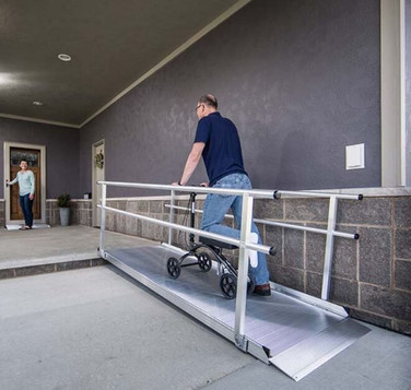 Man using a portable aluminum ramp to assist a wheelchair