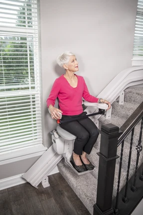 Senior woman using a Bruno stair lift on a staircase