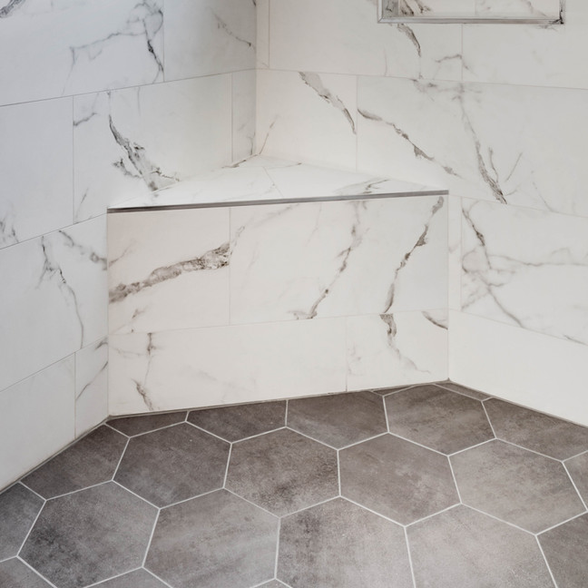 Tileable corner shower seat integrated into a modern bathroom design with marble tiles and hexagonal flooring