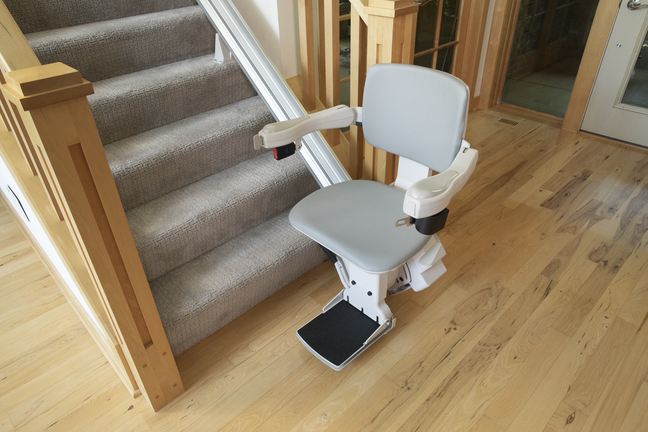 Bruno Elite straight stair lift positioned at the bottom of a staircase, with a comfortable seat, armrests