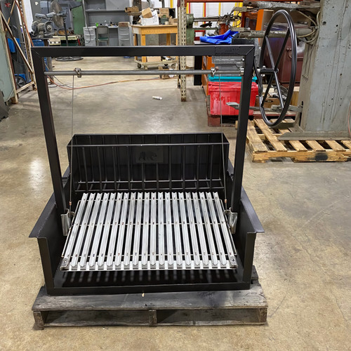 argentine wood-fired drop-in grill with sloped V-grate and rear brasero shown inside a metal frame firebox. argentine wood-fired drop-in grill with sloped V-grate and rear brasero shown inside a metal frame firebox.