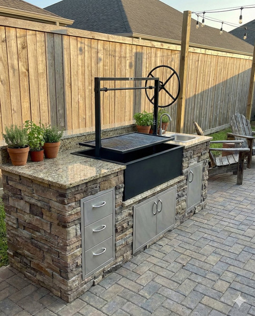 Custom outdoor kitchen featuring a NorCal Ovenworks Santa Maria wood-fired BBQ grill set in a residential backyard with stone masonry and pavers.