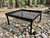 Removable expanded steel grill platform for campfire cooking on a rocky forest ground.