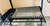 The adjustable height mechanism of the black steel Argentine grill, with the V-grate partially raised The adjustable height mechanism of the black steel Argentine grill, with the V-grate partially raised
