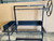 Front view of the Model #1047 black steel Argentine grill kit with side brasero against a wooden fence background. Front view of the Model #1047 black steel Argentine grill kit with side brasero against a wooden fence background.