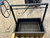 A close-up, top-down view of the black steel firebox interior, showing the round rod grilling grate.