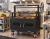 NorCal Ovenworks Unit #4446 Commercial Tiered Charbroiler Grill cooking in a restaurant kitchen under a commercial ventilation hood.