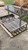 High-angle view of a stainless steel Argentine grill insert showing the V-grate cooking surface, side-mounted handwheel, and integrated fire basket for masonry installation.
