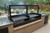 Black steel outdoor cooking system with two sections of V-grates, a substantial firebox, and a robust frame, emphasizing its durable construction.