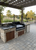 Built-in Argentine Grill featuring a black steel firebox, V-grate, and a stainless steel hand-crank wheel for height adjustment.
