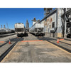 UltraTech Berm Builder (2) Corners, 6 inches, seen in this industrial setting with train tracks, railway cars, and steel structures.