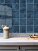 Marine blue square tiles used as a feature wall behind a kitchen counter with decorative styling