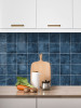 Marine blue peel and stick tiles installed as a modern kitchen splashback behind countertop and sink