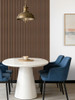 An elegant dining area with a round white table and blue chairs set against a rich Smoked Walnut slatted wall.