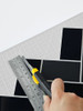 DIY home renovation showing easy cutting of Onyx Black Herringbone wall tiles.