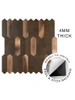 A hand removing the adhesive backing from a copper picket tile to demonstrate the easy DIY peel and stick installation.